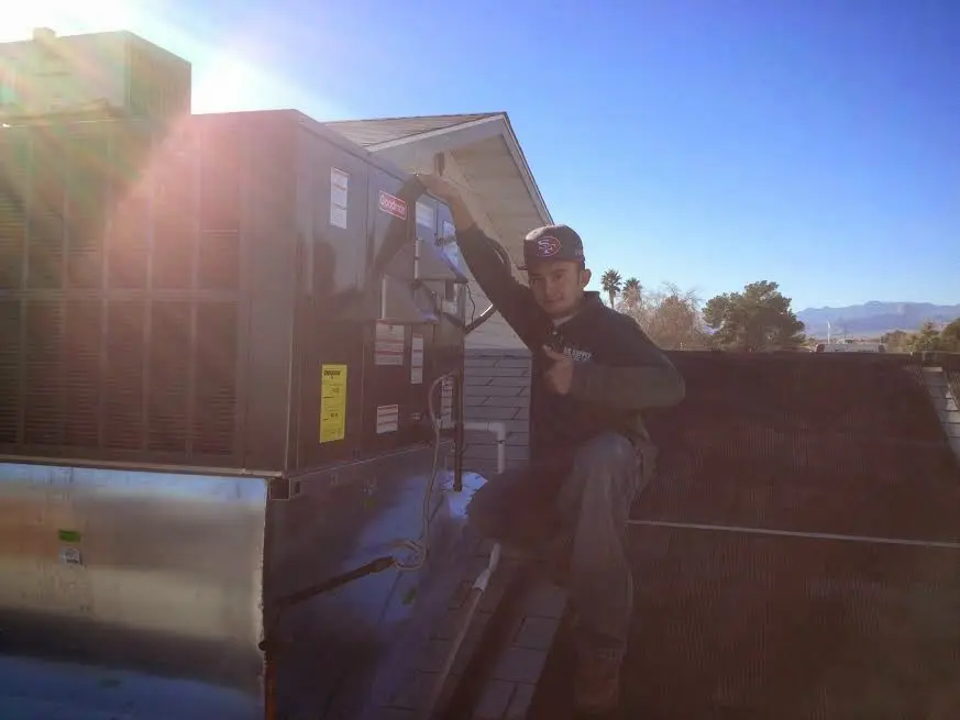 HVAC technician performing Air Duct Cleaning on a rooftop unit in Oswego